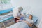 Professional nurse making an injection to a woman lying on operating table at the hospital preparing anesthetic medical