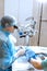 A professional ophthalmologist performs eye surgery with a microscope. The anesthesiologist controls the anesthesia and the