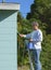 Professional painter or homeowner man on a ladder with paint can and brush painting the exterior of a residential house