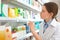 Professional pharmacist near shelves in drugstore