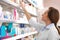 Professional pharmacist near shelves with medicines in drugstore