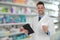 Professional pharmacist with pills and clipboard in drugstore
