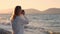 Professional photographer blonde young woman near sea on shore. sunset, unrecognizable girl photographs nature and ocean