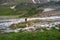 Professional photographer shoots a landscape standing on a small green island in the middle of a stormy mountain river. Green