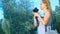 A professional photographer, takes pictures in an amusement park, a woman presses a button of a gadget among a flowering