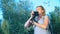 A professional photographer, takes pictures in an amusement park, a woman presses a button of a gadget among a flowering