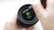 A professional photographer or video cameraman cleans the front glass of the photographic lens with a pen or a brush