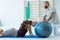 Professional physiotherapist exercising with an injured patient using a blue ball