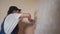 Professional plasterer female spackles the wall, applies and spreads plaster on a spatula in overalls and ball cap