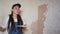 Professional plasterer female spackles the wall, applies and spreads plaster on a spatula in overalls and ball cap