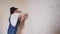 Professional plasterer female spackles the wall, applies and spreads plaster on a spatula in overalls and ball cap