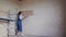 Professional plasterer female spackles the wall, applies and spreads plaster on a spatula in overalls and ball cap