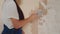 Professional plasterer female spackles the wall, applies and spreads plaster on a spatula in overalls and ball cap