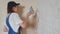 Professional plasterer female spackles the wall, applies and spreads plaster on a spatula in overalls and ball cap