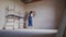 Professional plasterer female spackles the wall, applies and spreads plaster on a spatula in overalls and ball cap