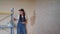 Professional plasterer female spackles the wall, applies and spreads plaster on a spatula in overalls and ball cap