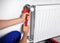 Professional plumber using adjustable wrench for installing new heating radiator indoors, closeup