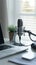 Professional podcast microphone setup with a laptop and green plant, clean modern design