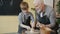 Professional potter senior man teaching boy to make ceramic vase on throwing wheel in studio