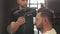 Professional and proper hair care. Cutting hair and beard. Hairdresser making hairstyle in male salon. Barber with dark