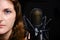 Professional record of the singer, close-up. Female vocalist on black background in recording Studio. Brunette girl for a silver