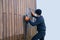 Professional renovation of hardwood cladding, man sanding, removing oxidation and dirt cleaning wood siding with an orbital power