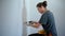 Professional repairwoman fixing socket with a screwdriver on a white wall