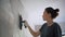 A professional repairwoman puts a plaster on the wall with a spatula.