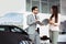 Professional salesperson selling cars at dealership to buyer