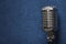 A professional shiny modern dynamic studio vocal microphone on a stylish dark blue grunge vintage background texture