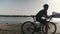 Professional skinny fit cyclist on bicycle looking on a bridge over river with cars moving through. Cyclist dreaming and thinking