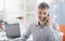 Professional smiling office worker sitting at desk and having a phone call with a smartphone, business and communication concept