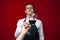 Professional sommelier offers a glass of red tasty wine on a red background, the guy the waiter gives the wine to the client,