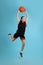 Professional sportswoman playing basketball on light blue background