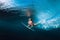 Professional surfer woman with surfboard dive underwater with under big ocean wave.