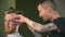 Professional tattooed barber giving a new haircut to his client in a barbershop