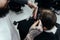 Professional tattooed barber using cutthroat razor cutting hair. Attractive male is getting a modern haircut in barber