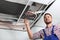 Professional technician repairing ceiling mounted air conditioner