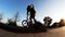 Professional teenager bicycler rides and jumps on his bike on brick wall curb