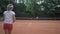 Professional tennis, couple of active teens play tennis and ball throwing each other over net on red court under rain