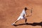 Professional tennis player performs forehand hit on clay tennis court. Junior tennis sport. Back view, copy space