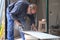 Professional tiler cutting a white ceramic tile with a radial saw.