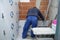Professional tiler placing white ceramic tiles on the wall.
