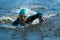 Professional triathlete swimming in river's open water. Man wearing swim equipment practicing triathlon on the beach in