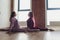 Professional two female athletes are sitting in yoga position together. They are touching their arms and looking at each