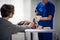 A professional vet doctor puts on rubber gloves to exam a dog, which is lying on the table, the huskys owner is patting