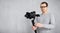 Professional videographer shooting video with modern dslr camera on 3-axis gimbal over grey concrete wall background