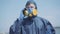 Professional virologist in biohazard suit and respirator talking on phone. Portrait of confident young Caucasian man