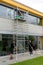 Professional window washers move a portable scaffolding along a house front during a window cleaning job