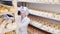 Professional woman cheesemaker checking aging process of hard goat cheese in special maturing chamber at dairy